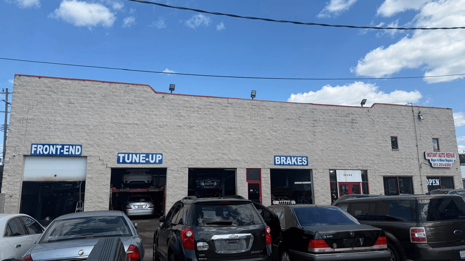 The front of Instant Auto Repair showing the Front-End, Tune-Up and Brakes bays open with vehicles up on the lifts