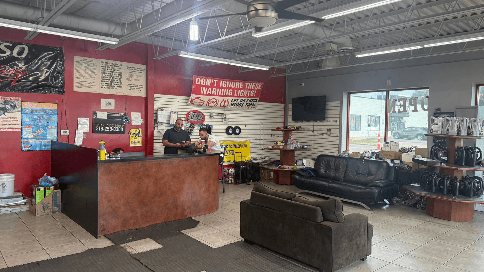 The front counter and waiting area at Instant Auto Repair, with staff at the desk and a banner reading do not ignore these warning lights